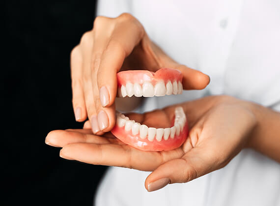 person holding a set of dentures