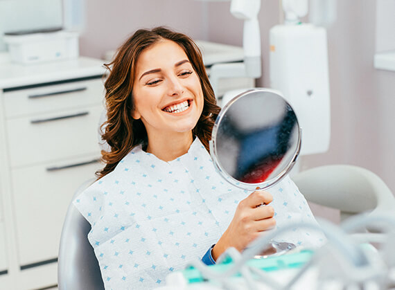 woman examining her smile in a mirror