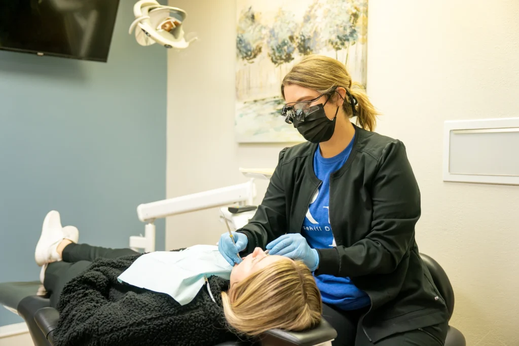 Dental hygienist doing a gentle teeth cleaning on a patient in the dental chair | Locally-owned dentist in Lenexa, KS