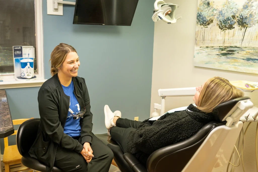 Friendly staff interacting with smiling patient | Locally-owned dentist in Lenexa, KS