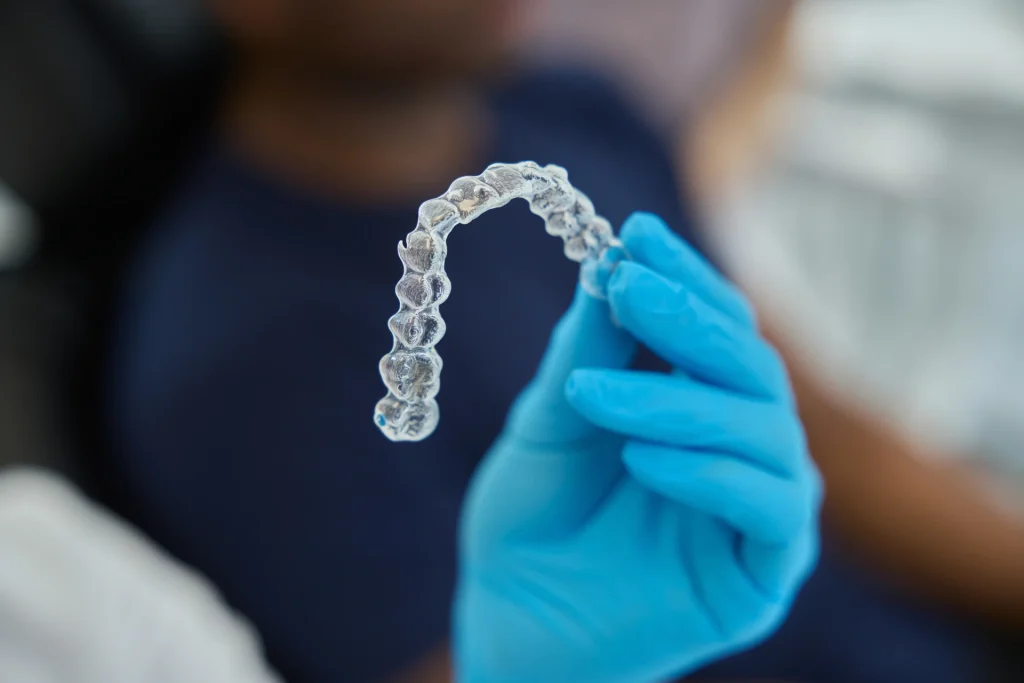 Close up photo of a dentist holding clear aligner tray